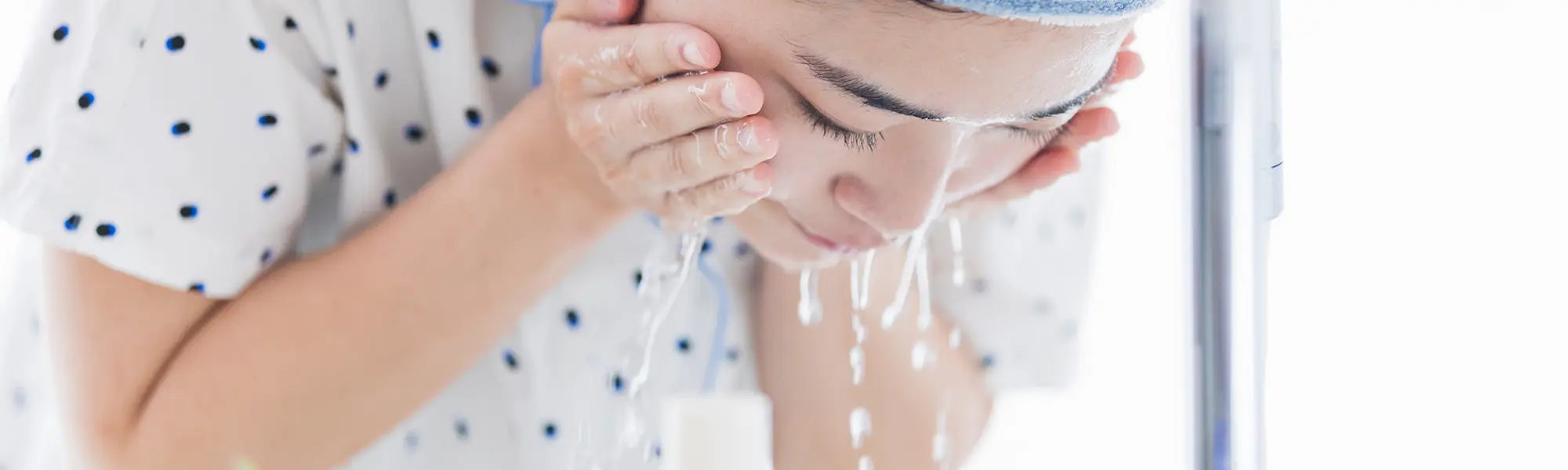 洗面所で顔を洗う女性